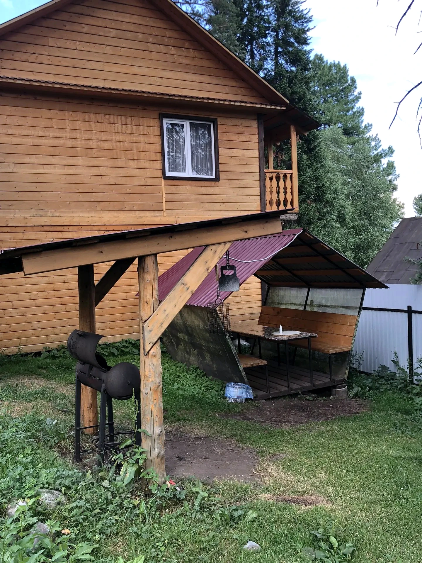 Крытая беседка и мангал рядом с деревянным домом